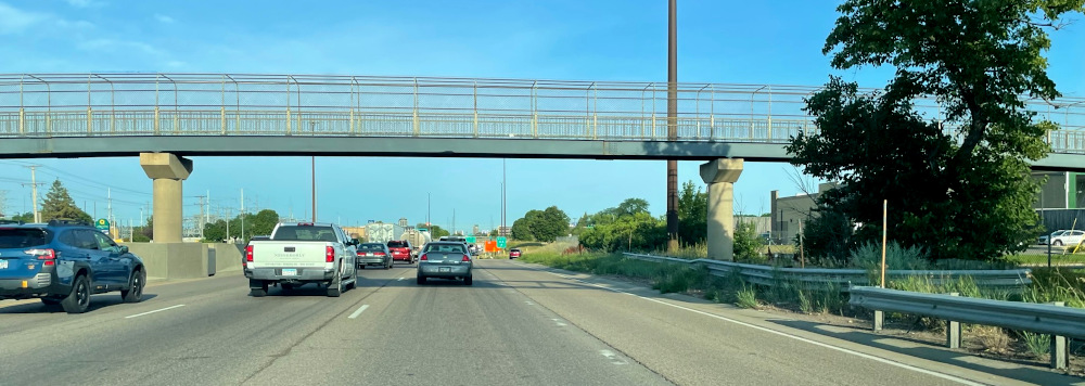 A photo of a pedestrian bridge over an interstate taken from a car on the road.